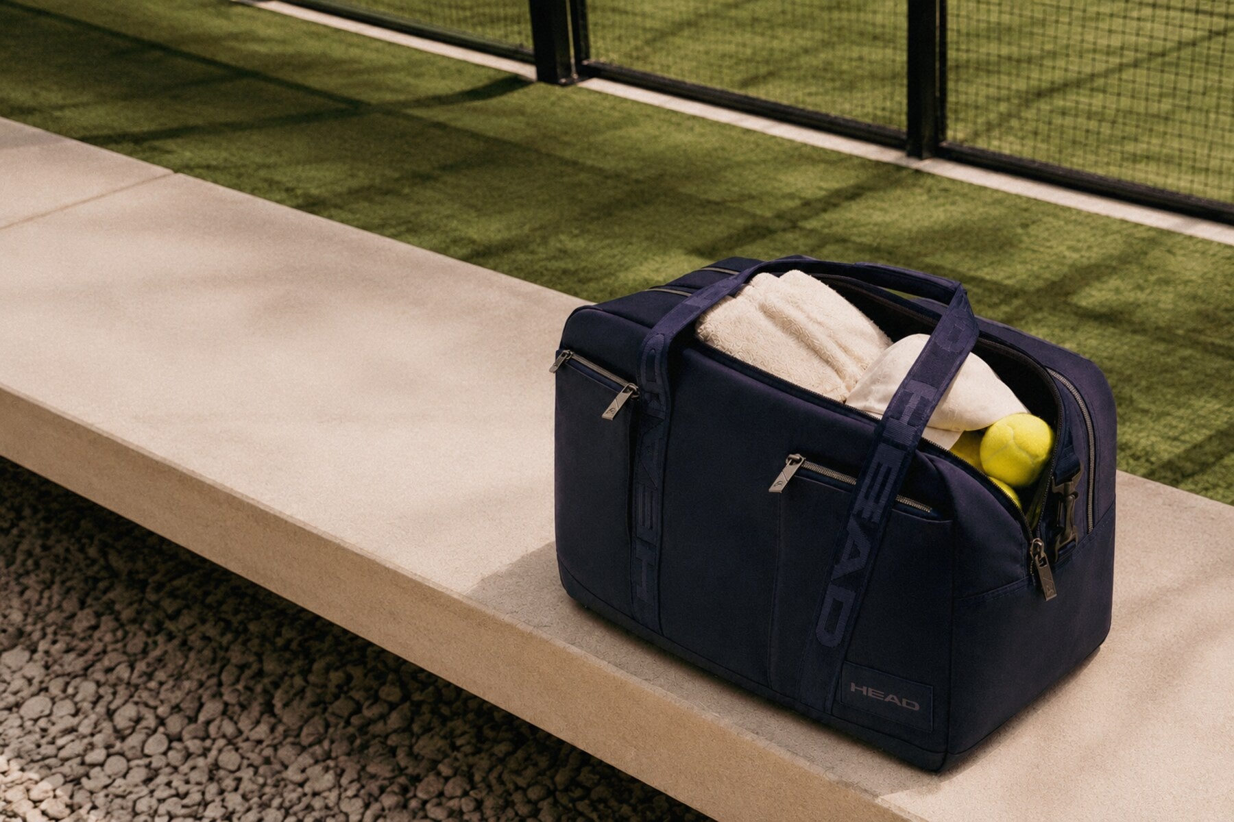 HEAD padel bag beside an outdoor court